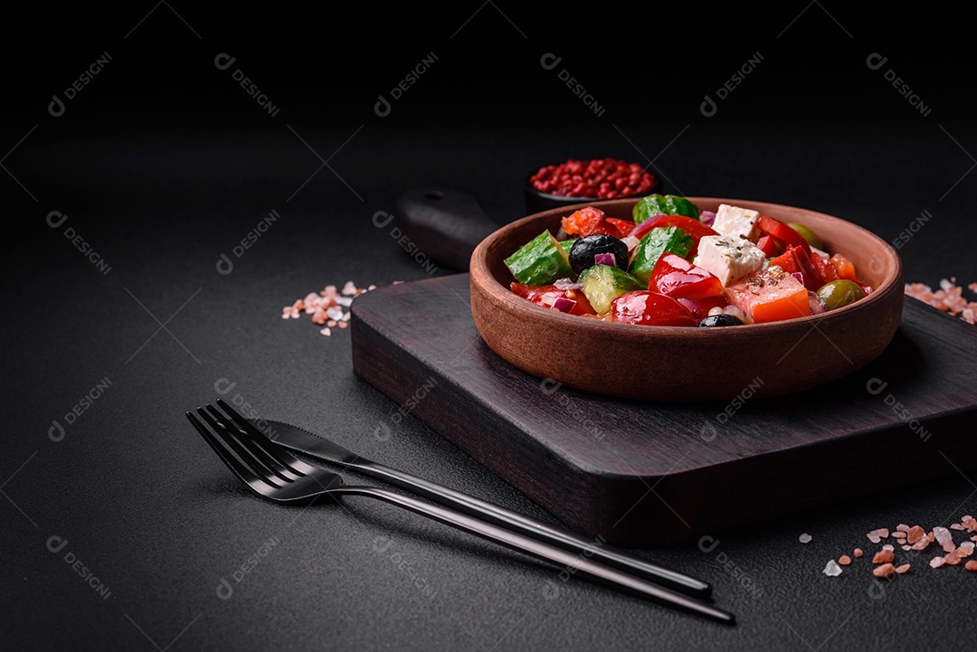 Salada grega deliciosa e fresca com queijo feta, azeitonas, tomates e pepinos sobre um fundo escuro de concreto