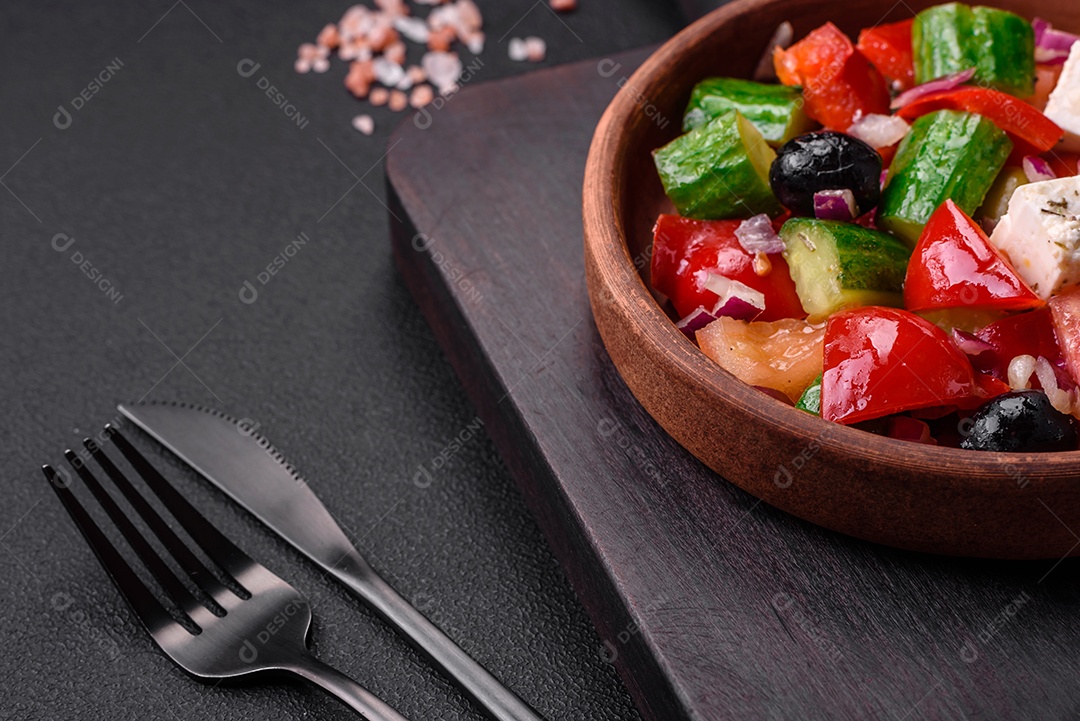 Salada grega deliciosa e fresca com queijo feta, azeitonas, tomates e pepinos sobre um fundo escuro de concreto