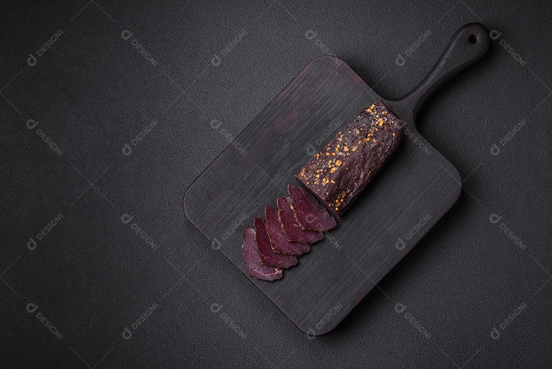 Delicioso basturma armênio defumado com especiarias e ervas cortadas em um fundo escuro de concreto