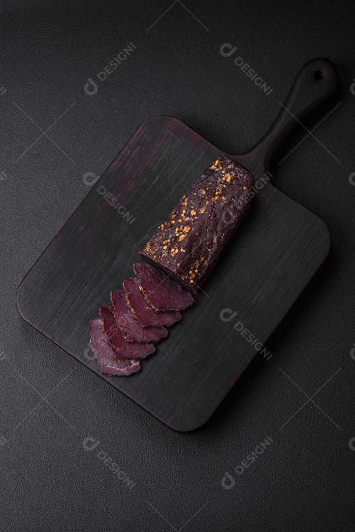 Delicioso basturma armênio defumado com especiarias e ervas cortadas em um fundo escuro de concreto