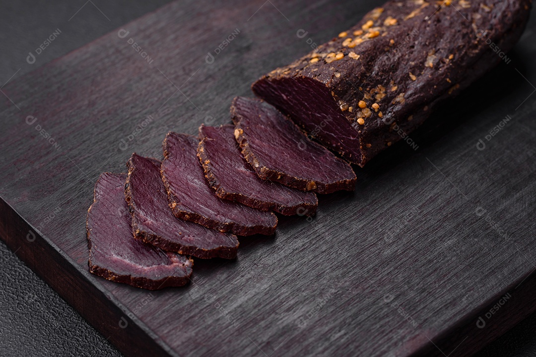 Delicioso basturma armênio defumado com especiarias e ervas cortadas em um fundo escuro de concreto