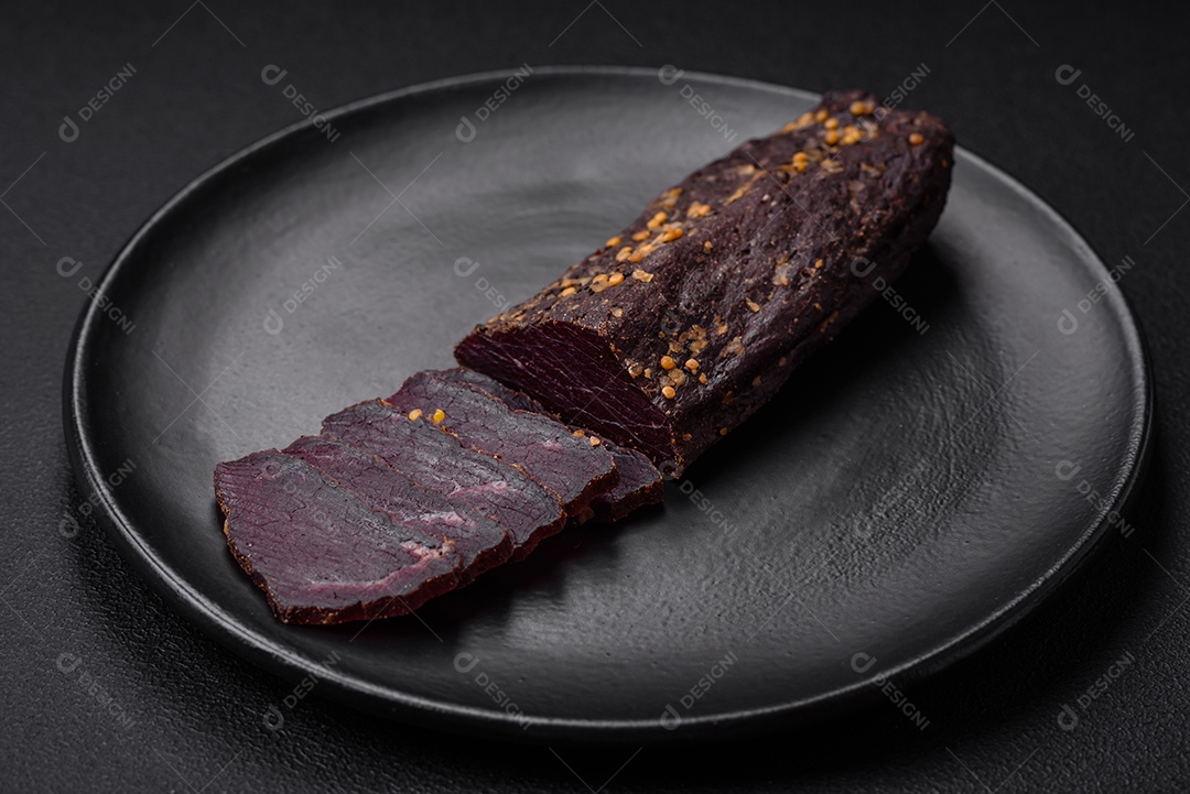 Delicioso basturma armênio defumado com especiarias e ervas cortadas em um fundo escuro de concreto