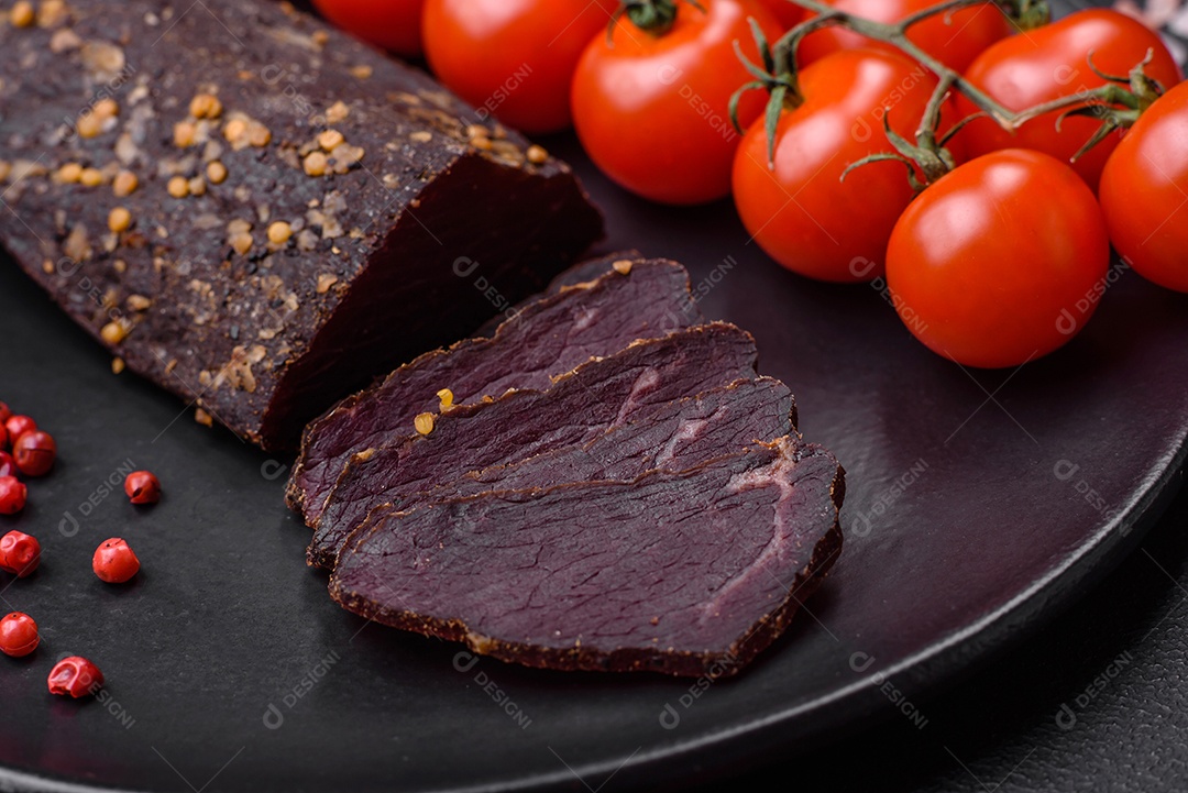 Delicioso basturma armênio defumado com especiarias e ervas cortadas em um fundo escuro de concreto