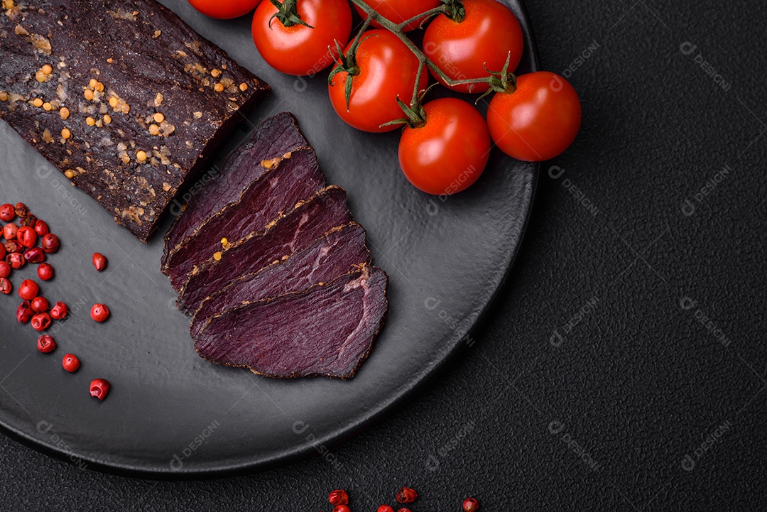 Delicioso basturma armênio defumado com especiarias e ervas cortadas em um fundo escuro de concreto