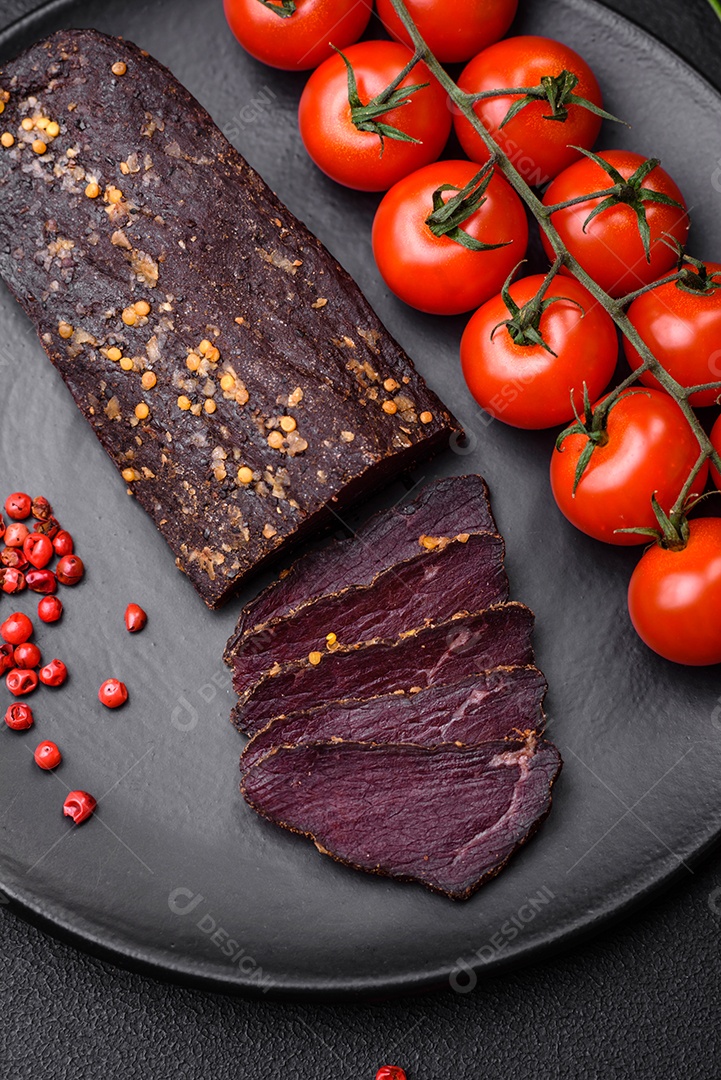 Delicioso basturma armênio defumado com especiarias e ervas cortadas em um fundo escuro de concreto