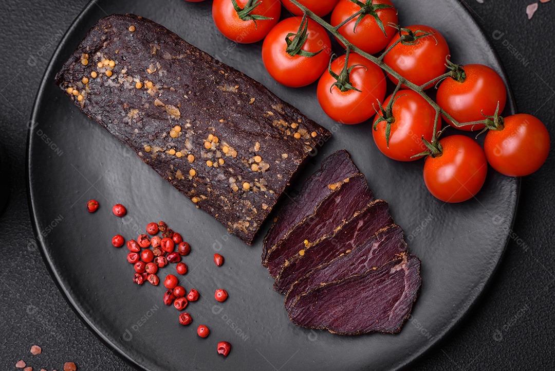 Delicioso basturma armênio defumado com especiarias e ervas cortadas em um fundo escuro de concreto