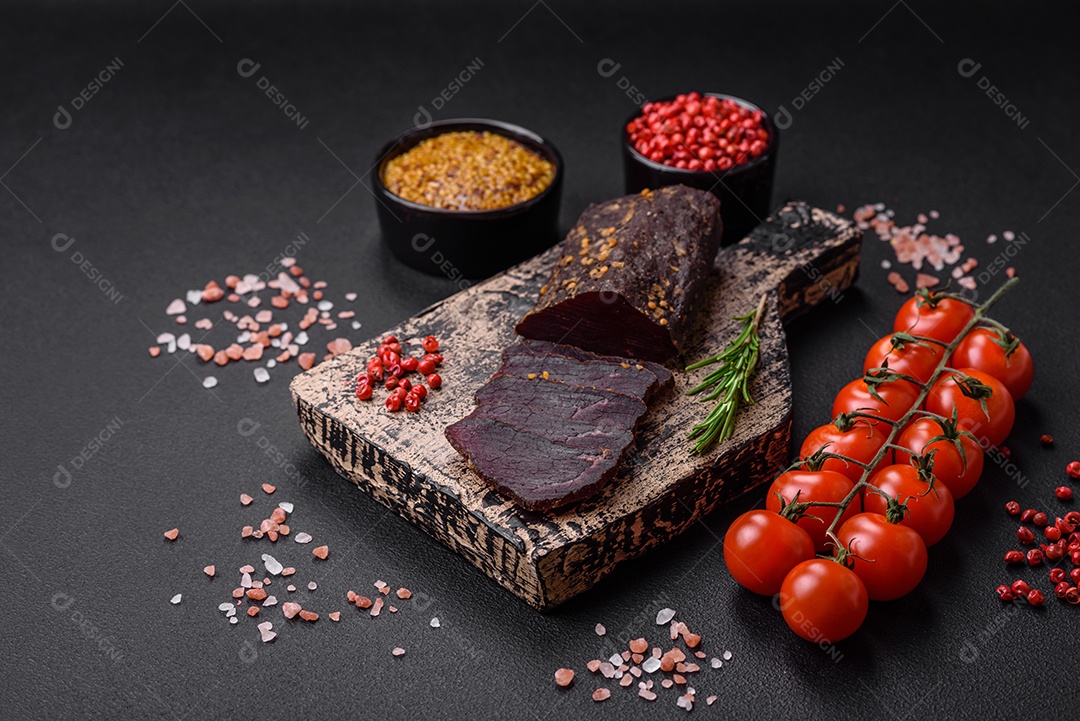 Delicioso basturma armênio defumado com especiarias e ervas cortadas em um fundo escuro de concreto