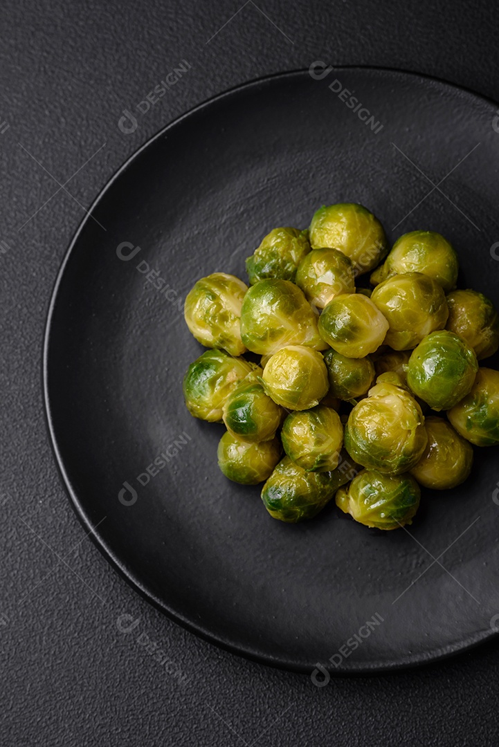 Deliciosas couves de Bruxelas cozidas em um prato de cerâmica sobre um fundo escuro de concreto. Comida vegetariana