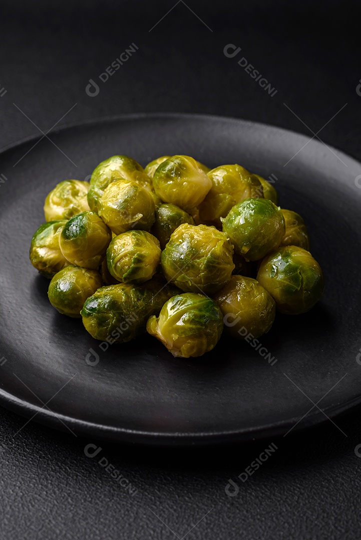 Deliciosas couves de Bruxelas cozidas em um prato de cerâmica sobre um fundo escuro de concreto. Comida vegetariana