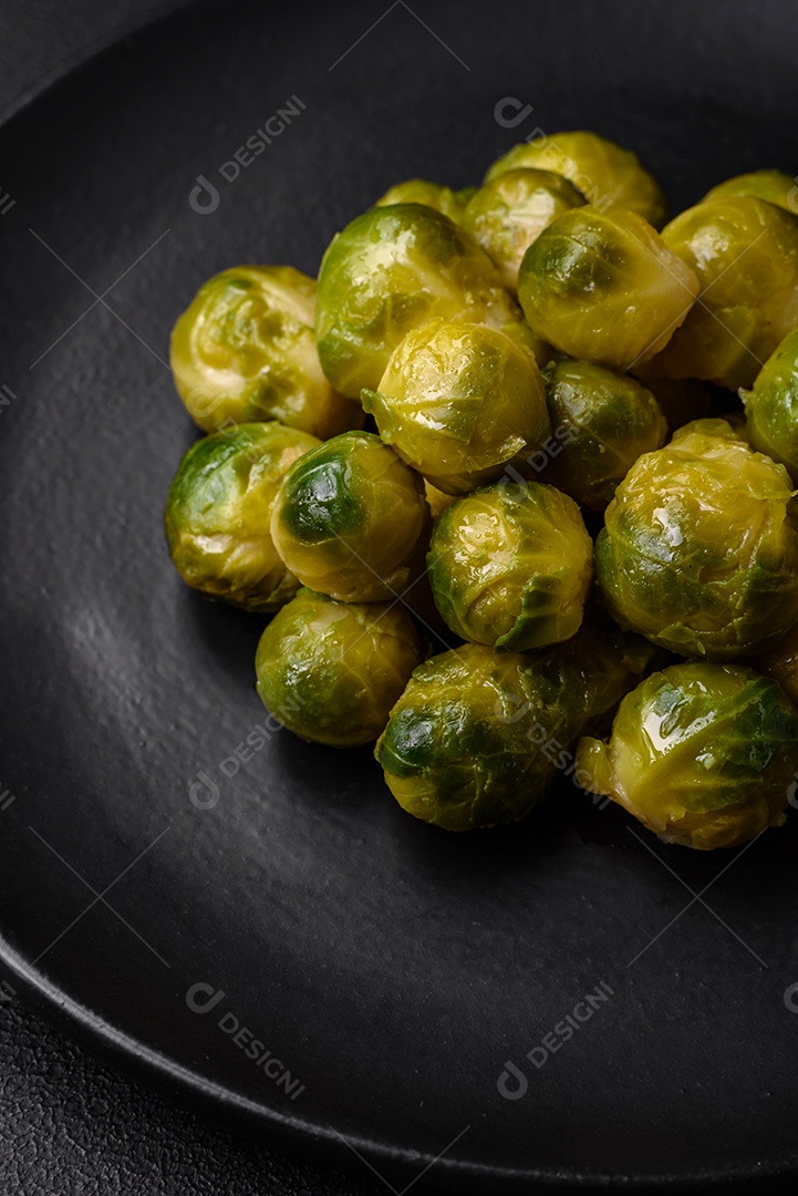 Deliciosas couves de Bruxelas cozidas em um prato de cerâmica sobre um fundo escuro de concreto. Comida vegetariana