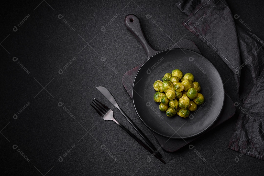 Deliciosas couves de Bruxelas cozidas em um prato de cerâmica sobre um fundo escuro de concreto. Comida vegetariana