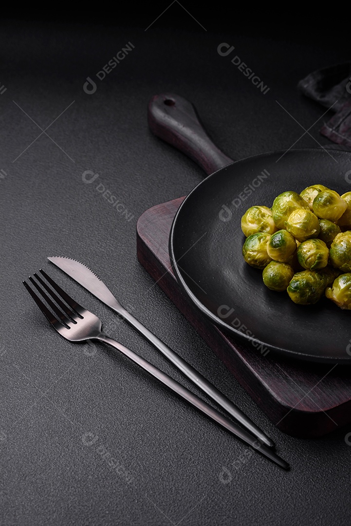 Deliciosas couves de Bruxelas cozidas em um prato de cerâmica sobre um fundo escuro de concreto. Comida vegetariana