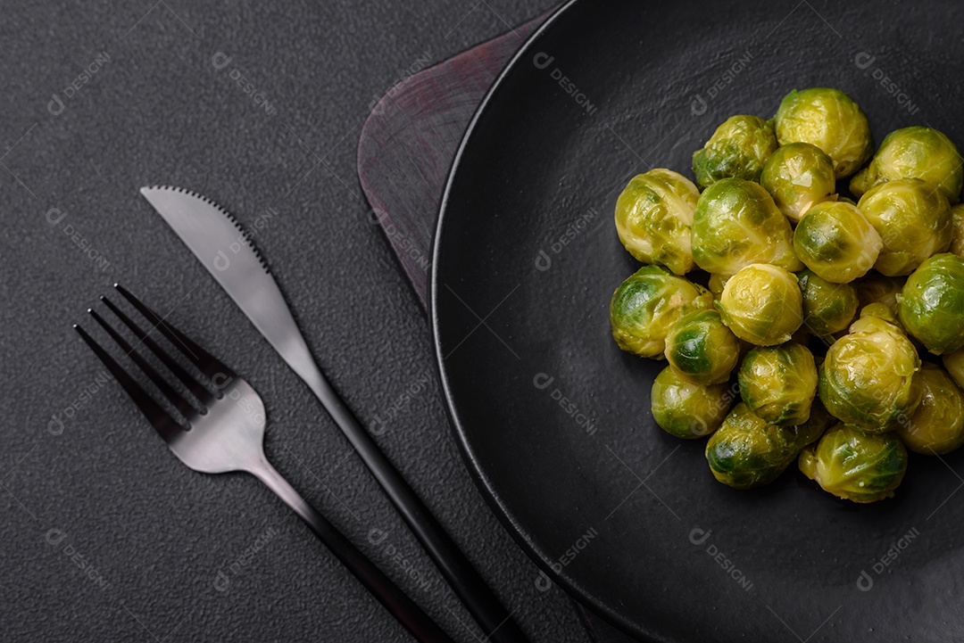 Deliciosas couves de Bruxelas cozidas em um prato de cerâmica sobre um fundo escuro de concreto. Comida vegetariana