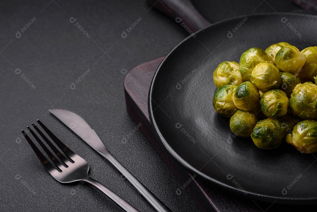 Deliciosas couves de Bruxelas cozidas em um prato de cerâmica sobre um fundo escuro de concreto. Comida vegetariana