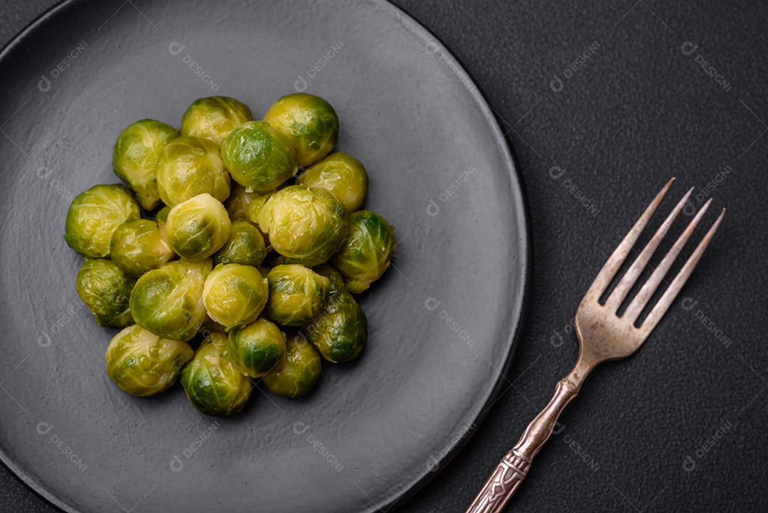 Deliciosas couves de Bruxelas cozidas em um prato de cerâmica sobre um fundo escuro de concreto. Comida vegetariana