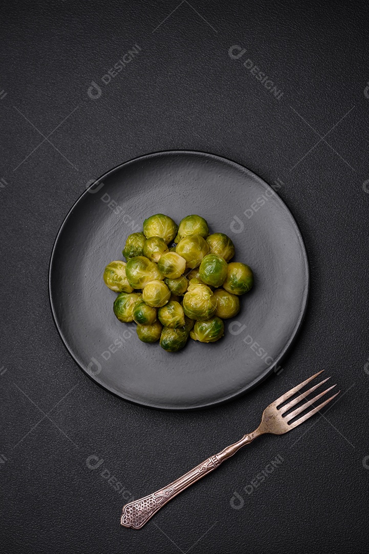 Deliciosas couves de Bruxelas cozidas em um prato de cerâmica sobre um fundo escuro de concreto. Comida vegetariana