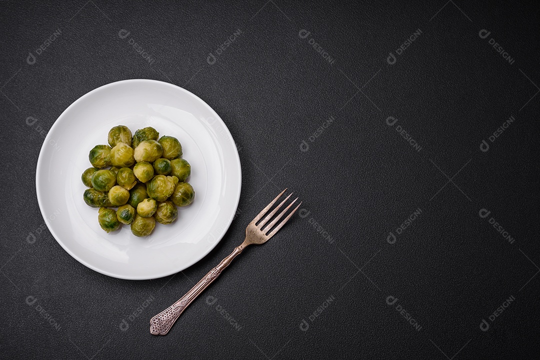 Deliciosas couves de Bruxelas cozidas em um prato de cerâmica sobre um fundo escuro de concreto. Comida vegetariana