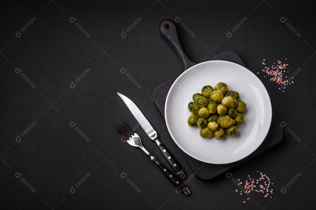 Deliciosas couves de Bruxelas cozidas em um prato de cerâmica sobre um fundo escuro de concreto. Comida vegetariana