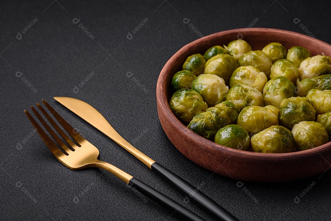Deliciosas couves de Bruxelas cozidas em um prato de cerâmica sobre um fundo escuro de concreto. Comida vegetariana