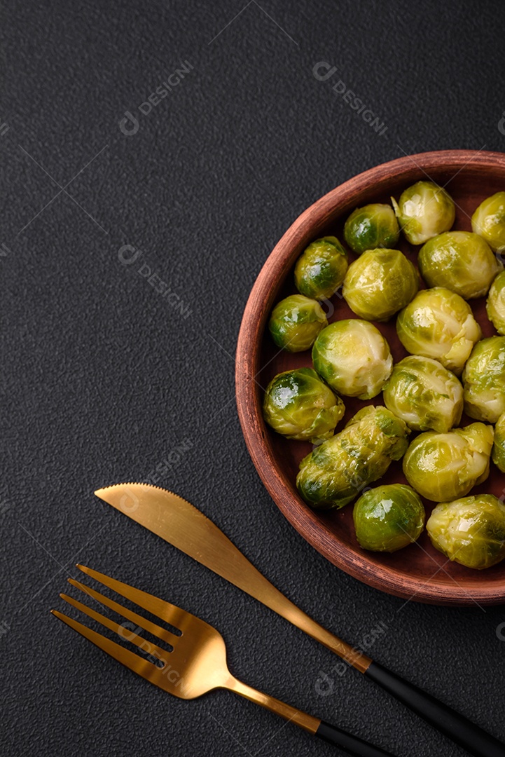 Deliciosas couves de Bruxelas cozidas em um prato de cerâmica sobre um fundo escuro de concreto. Comida vegetariana