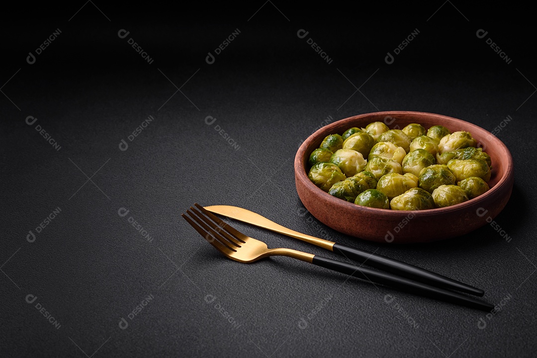 Deliciosas couves de Bruxelas cozidas em um prato de cerâmica sobre um fundo escuro de concreto. Comida vegetariana