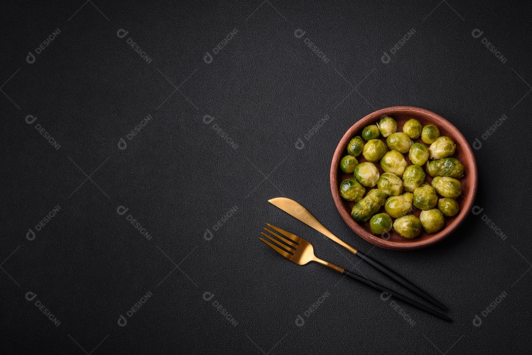 Deliciosas couves de Bruxelas cozidas em um prato de cerâmica sobre um fundo escuro de concreto. Comida vegetariana