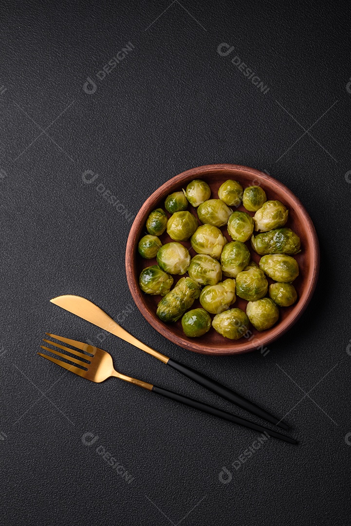 Deliciosas couves de Bruxelas cozidas em um prato de cerâmica sobre um fundo escuro de concreto. Comida vegetariana