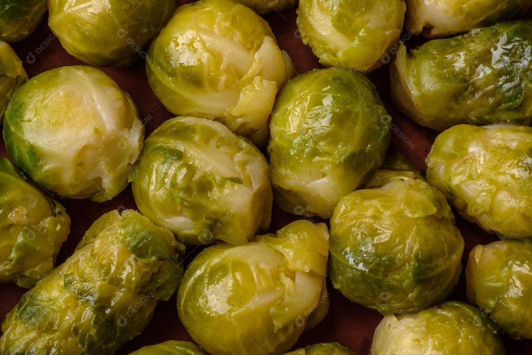 Deliciosas couves de Bruxelas cozidas em um prato de cerâmica sobre um fundo escuro de concreto. Comida vegetariana
