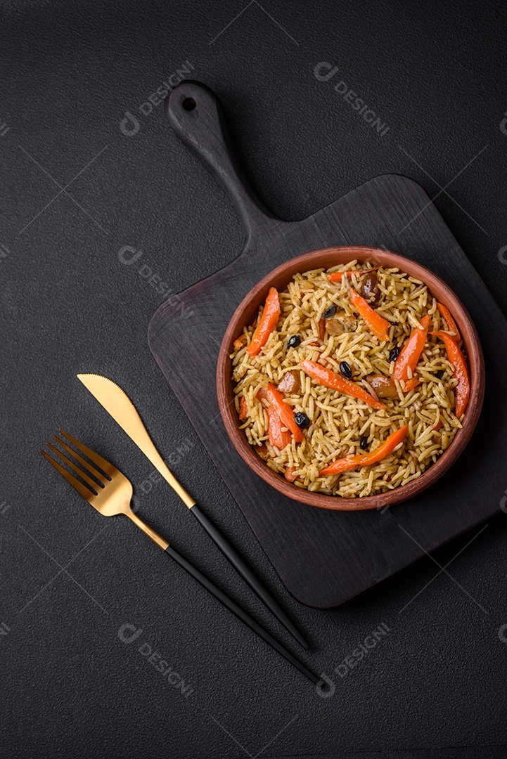Delicioso pilaf uzbeque com frango, cenoura, bérberis, especiarias e ervas sobre um fundo escuro de concreto