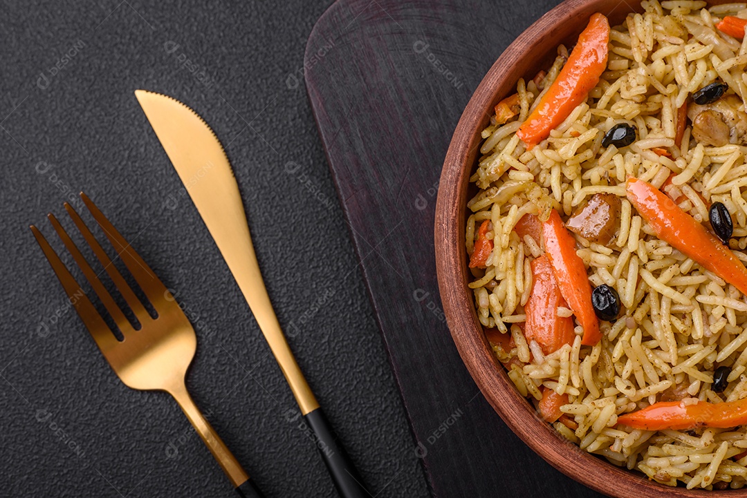 Delicioso pilaf uzbeque com frango, cenoura, bérberis, especiarias e ervas sobre um fundo escuro de concreto
