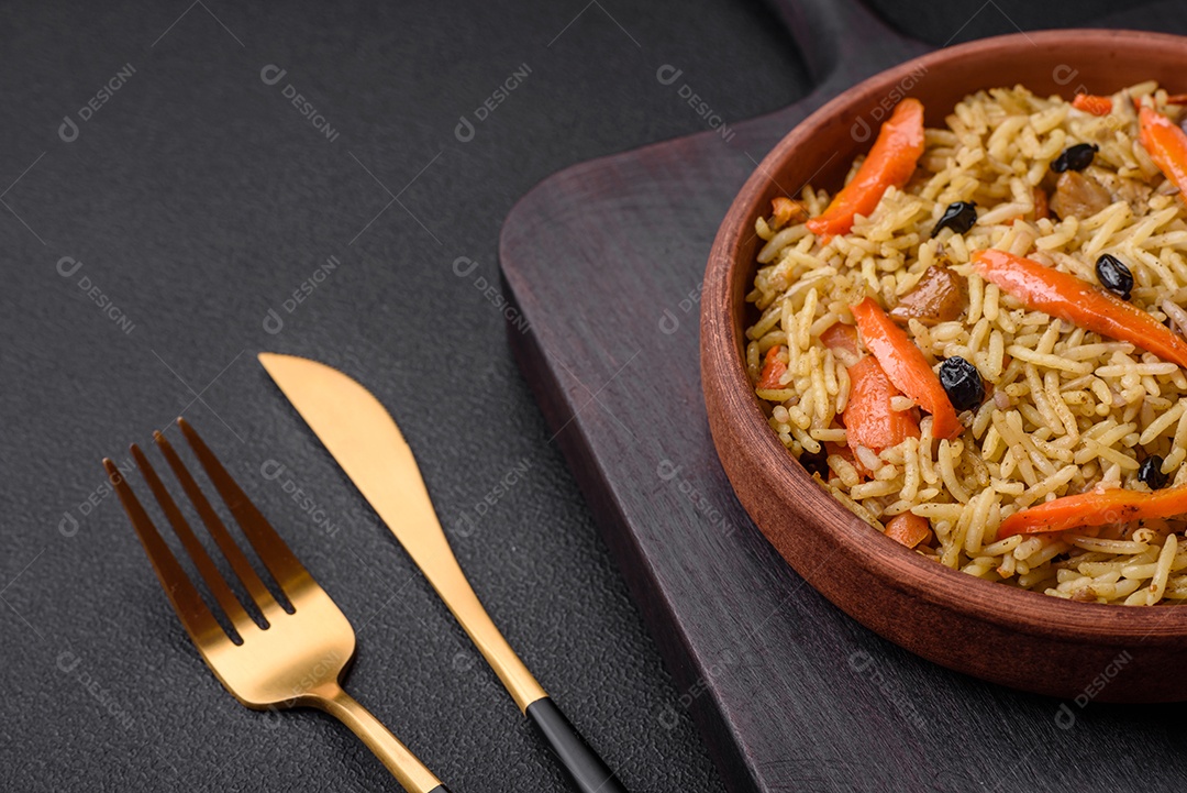 Delicioso pilaf uzbeque com frango, cenoura, bérberis, especiarias e ervas sobre um fundo escuro de concreto