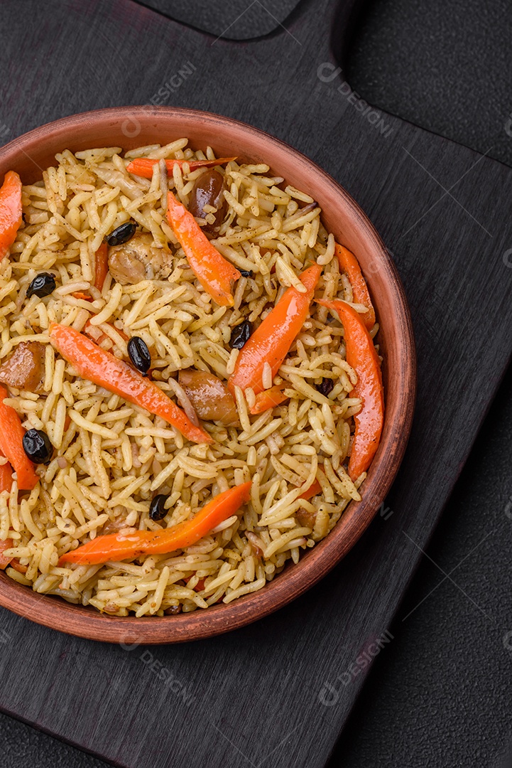Delicioso pilaf uzbeque com frango, cenoura, bérberis, especiarias e ervas sobre um fundo escuro de concreto