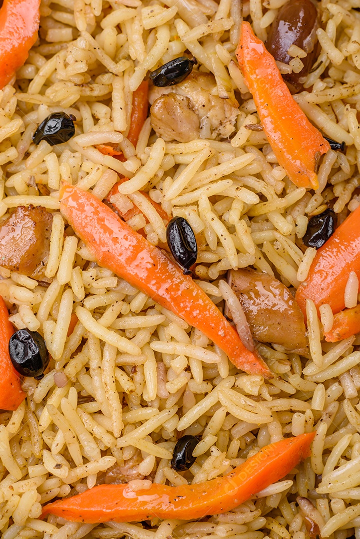 Delicioso pilaf uzbeque com frango, cenoura, bérberis, especiarias e ervas sobre um fundo escuro de concreto