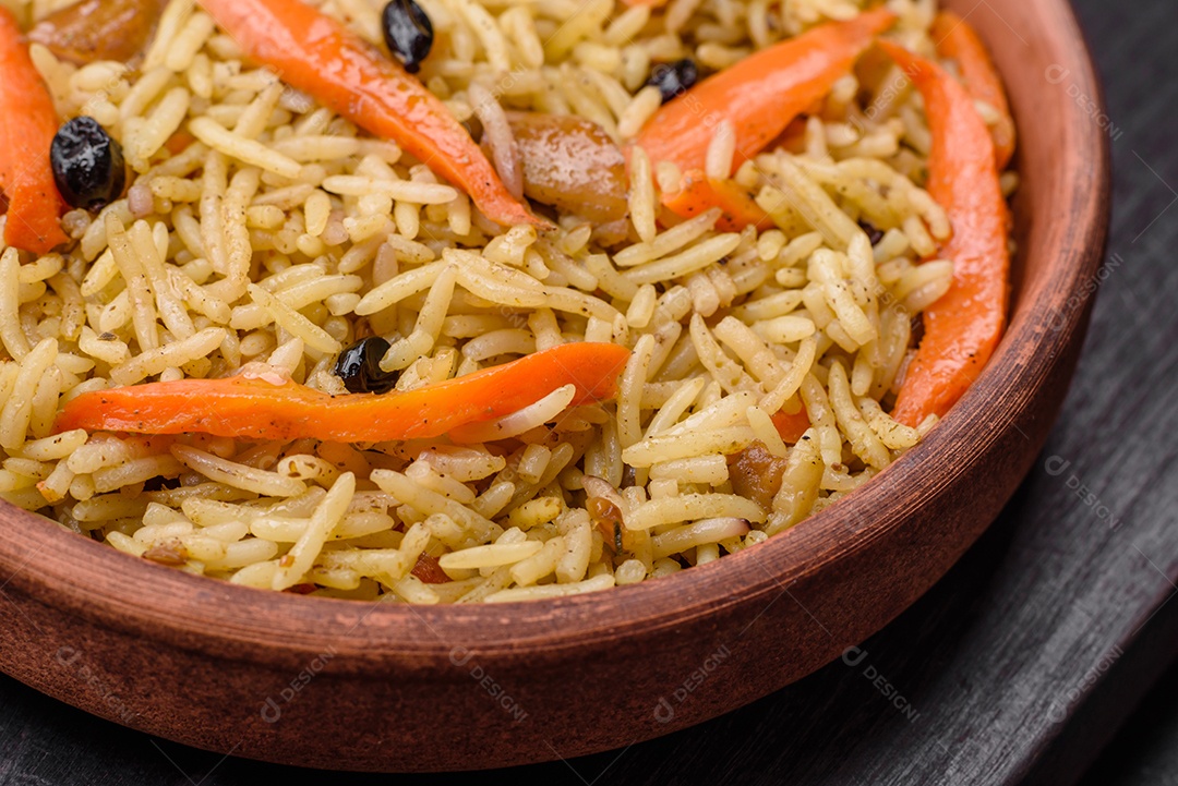 Delicioso pilaf uzbeque com frango, cenoura, bérberis, especiarias e ervas sobre um fundo escuro de concreto