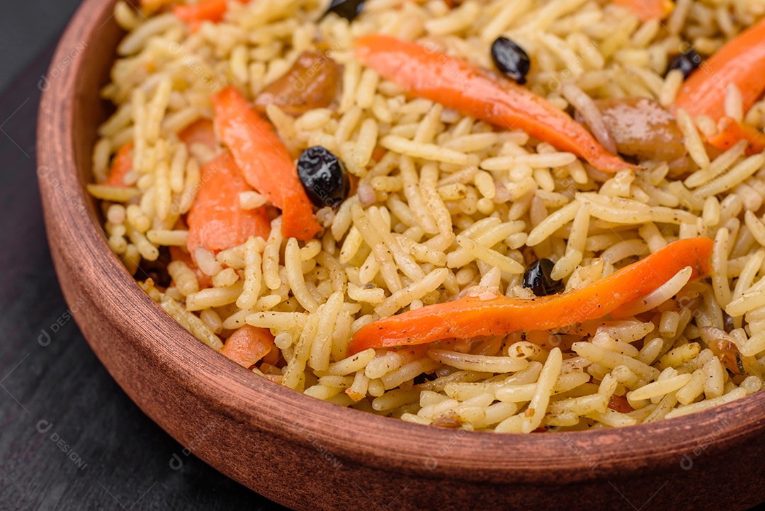 Delicioso pilaf uzbeque com frango, cenoura, bérberis, especiarias e ervas sobre um fundo escuro de concreto