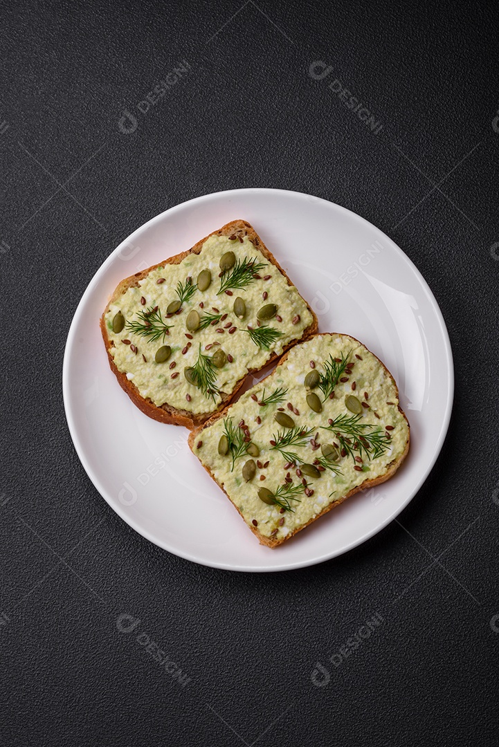 Torradas grelhadas com pasta de abacate, ovos, cream cheese, sal, especiarias e ervas sobre uma mesa de concreto texturizado