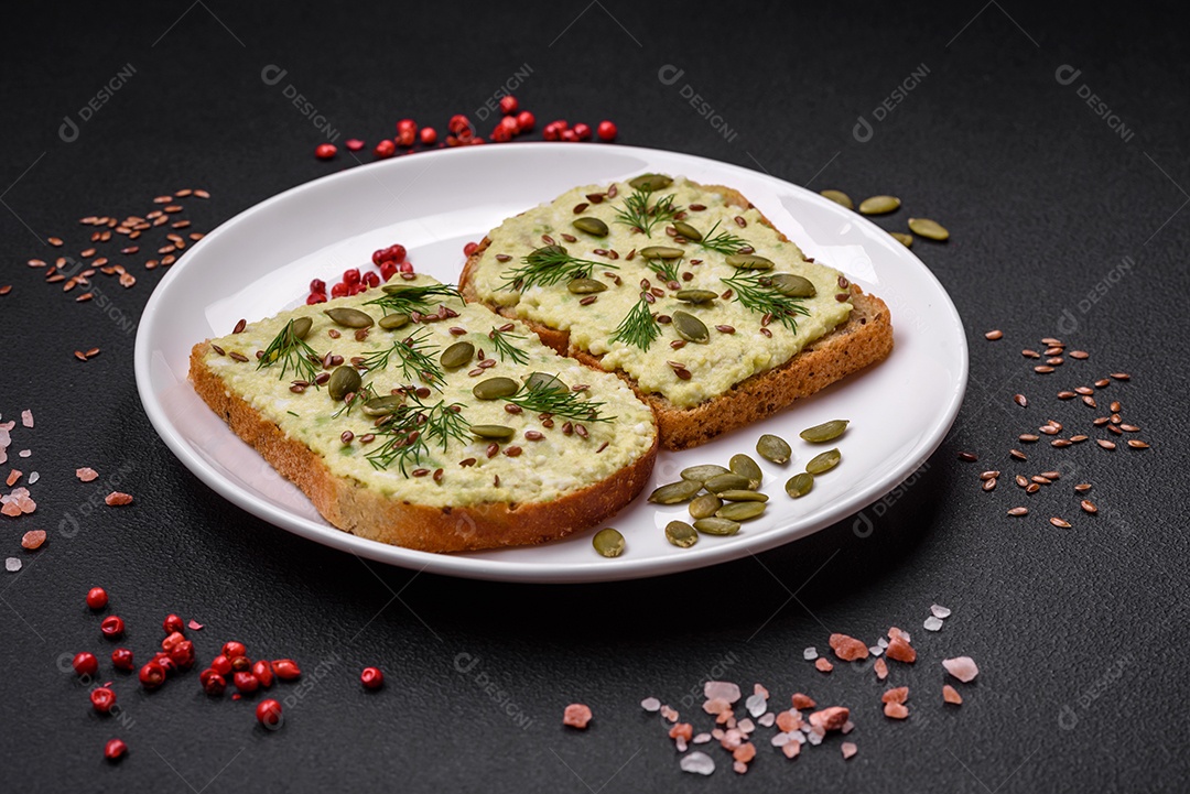 Torradas grelhadas com pasta de abacate, ovos, cream cheese, sal, especiarias e ervas sobre uma mesa de concreto texturizado