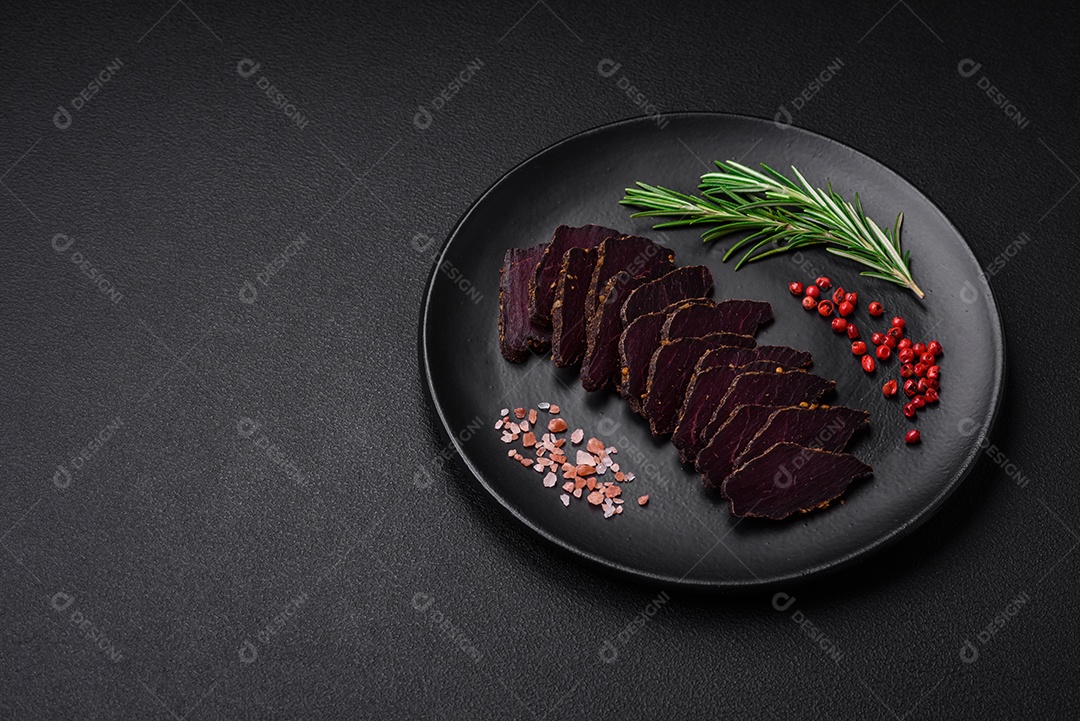 Deliciosa carne seca defumada ou carne seca de cavalo com especiarias e sal sobre um fundo escuro de concreto