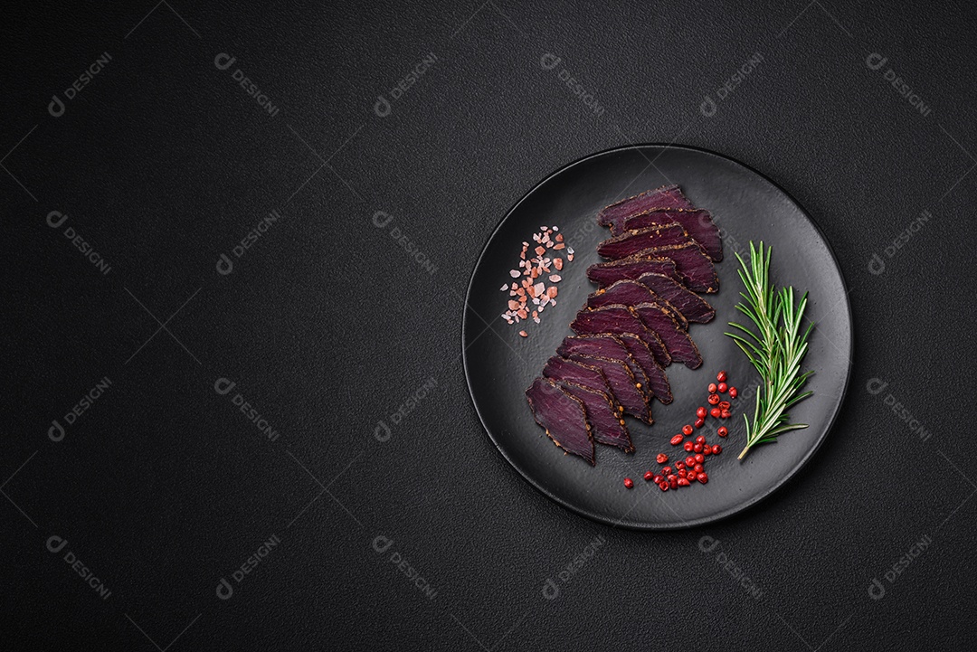 Deliciosa carne seca defumada ou carne seca de cavalo com especiarias e sal sobre um fundo escuro de concreto