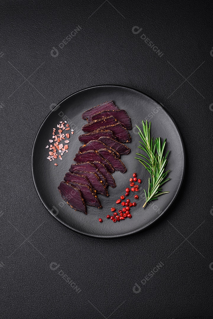 Deliciosa carne seca defumada ou carne seca de cavalo com especiarias e sal sobre um fundo escuro de concreto