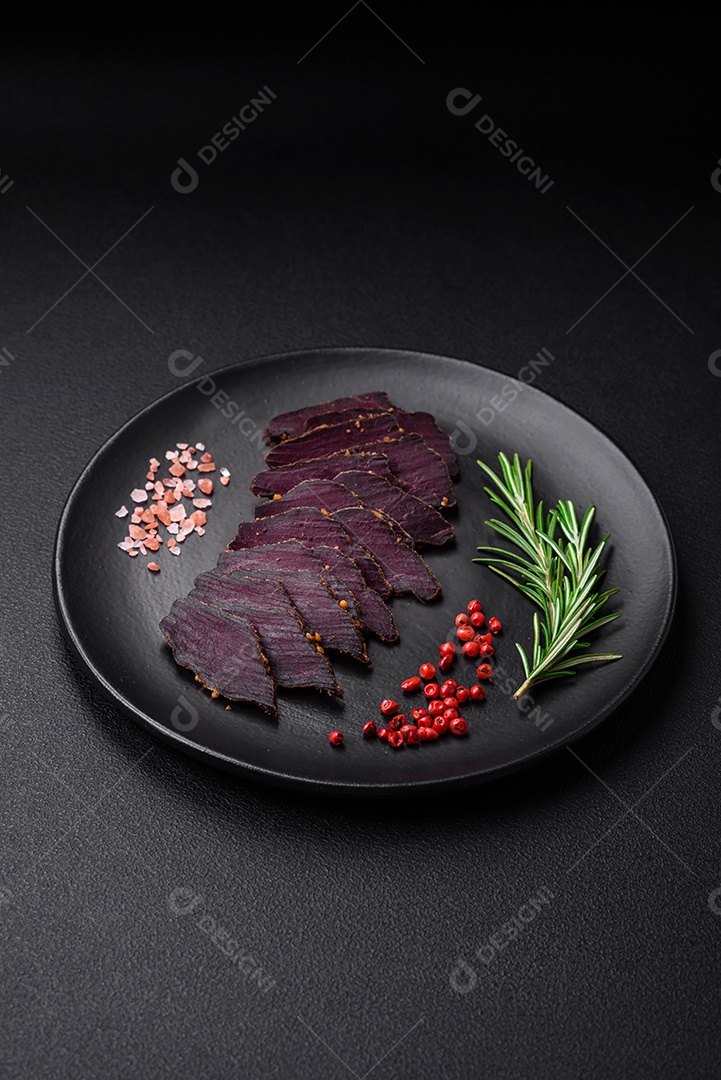 Deliciosa carne seca defumada ou carne seca de cavalo com especiarias e sal sobre um fundo escuro de concreto