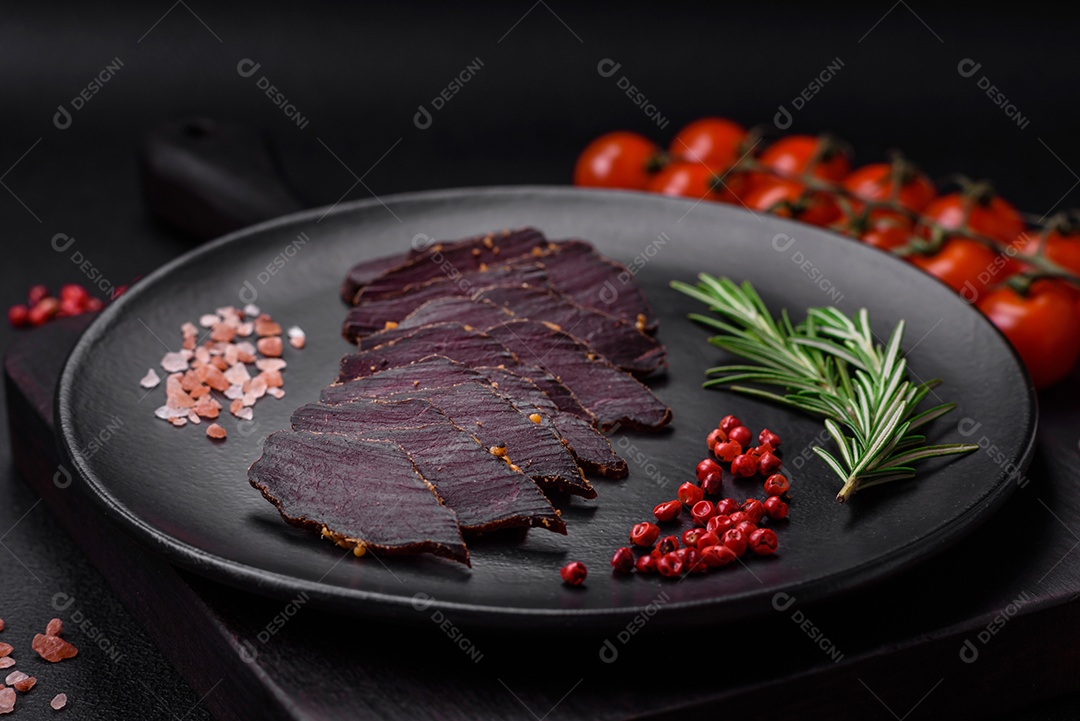 Deliciosa carne seca defumada ou carne seca de cavalo com especiarias e sal sobre um fundo escuro de concreto