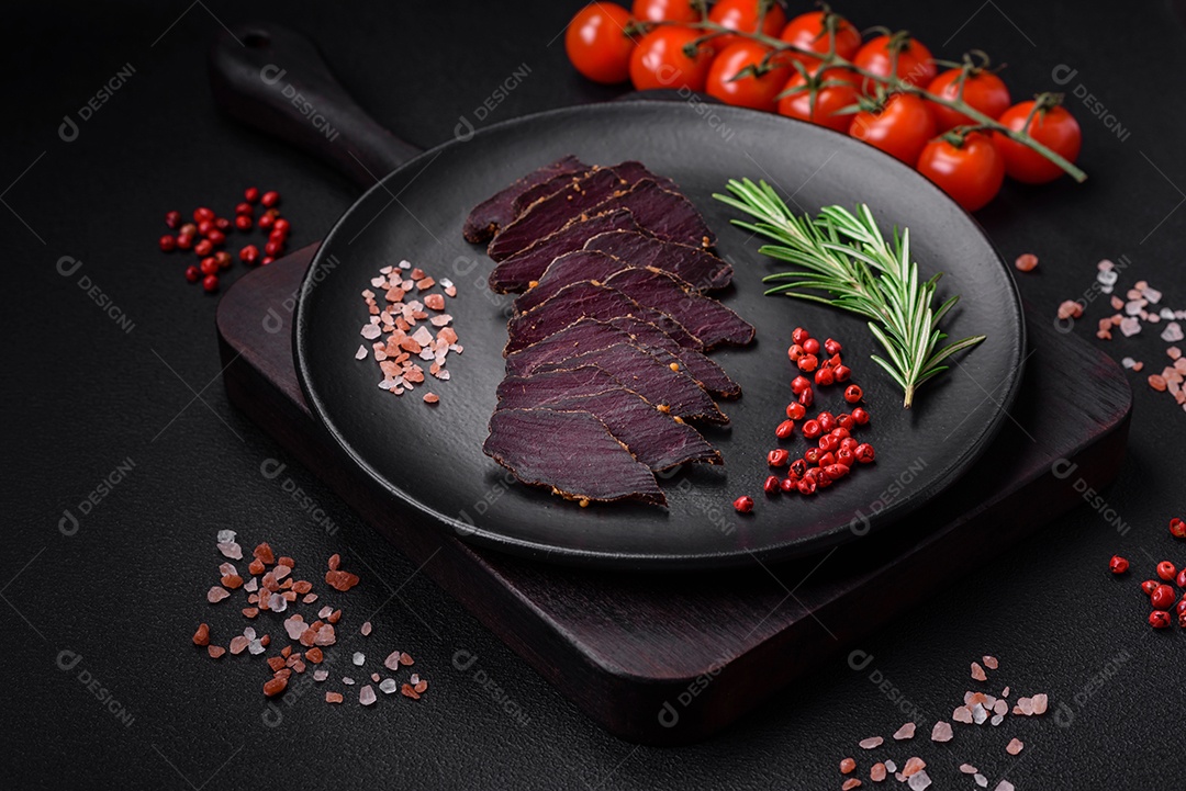 Deliciosa carne seca defumada ou carne seca de cavalo com especiarias e sal sobre um fundo escuro de concreto