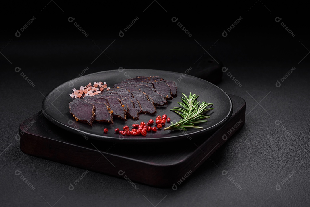 Deliciosa carne seca defumada ou carne seca de cavalo com especiarias e sal sobre um fundo escuro de concreto