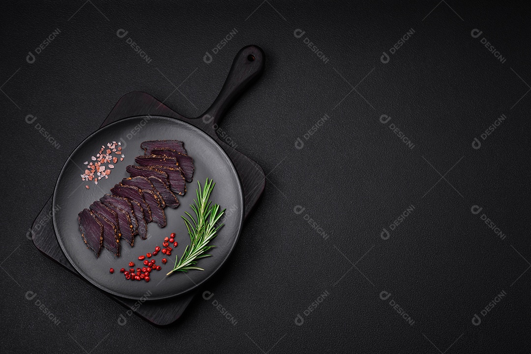 Deliciosa carne seca defumada ou carne seca de cavalo com especiarias e sal sobre um fundo escuro de concreto