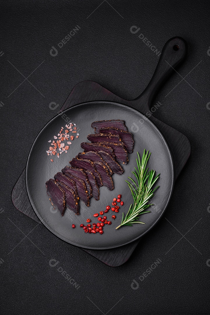 Deliciosa carne seca defumada ou carne seca de cavalo com especiarias e sal sobre um fundo escuro de concreto