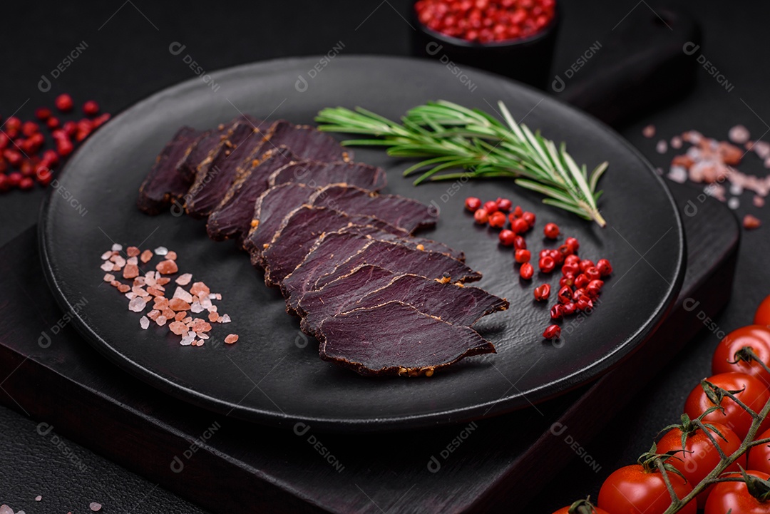 Deliciosa carne seca defumada ou carne seca de cavalo com especiarias e sal sobre um fundo escuro de concreto