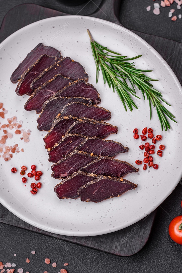 Deliciosa carne seca defumada ou carne seca de cavalo com especiarias e sal sobre um fundo escuro de concreto