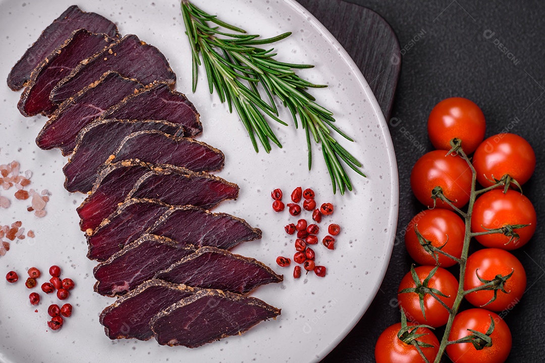 Deliciosa carne seca defumada ou carne seca de cavalo com especiarias e sal sobre um fundo escuro de concreto