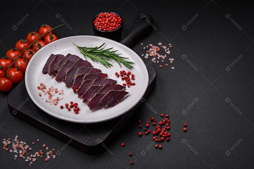 Deliciosa carne seca defumada ou carne seca de cavalo com especiarias e sal sobre um fundo escuro de concreto